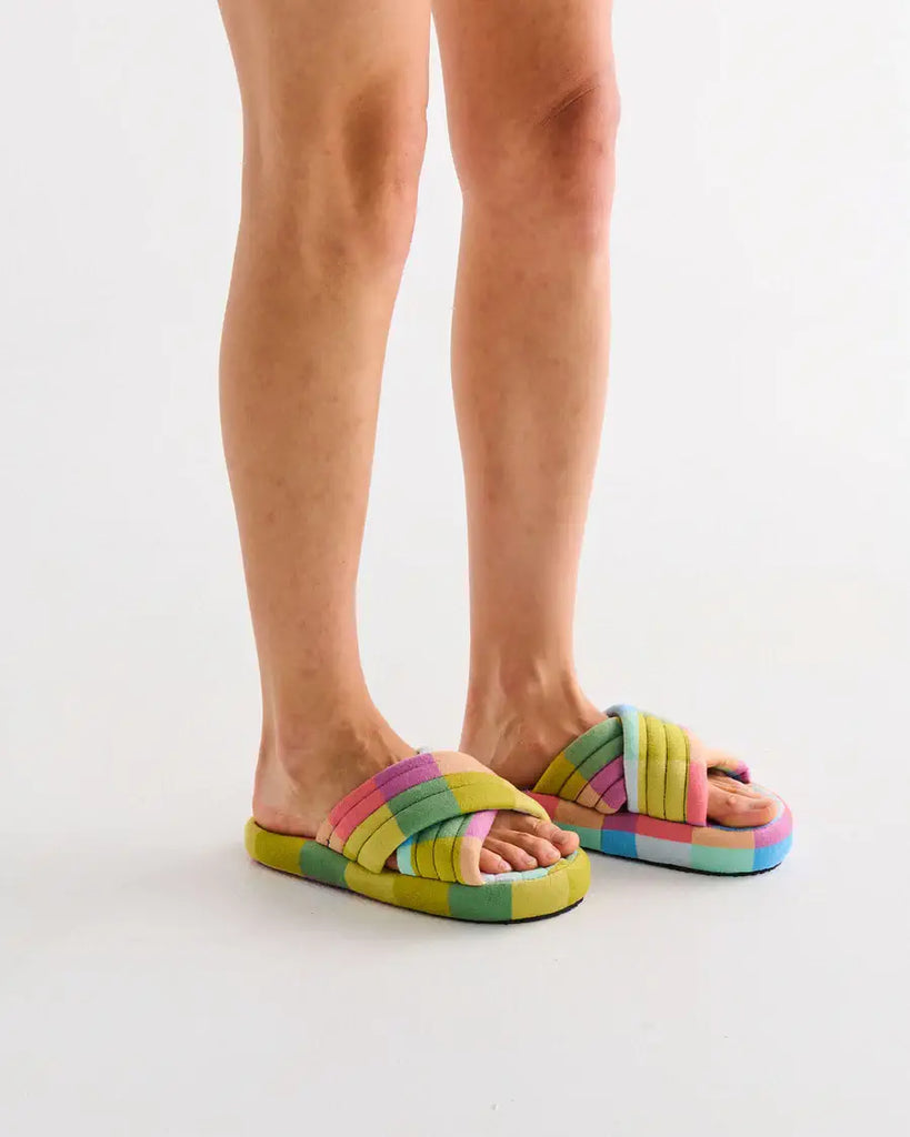 Colorful sandals worn by a person on a light gray background