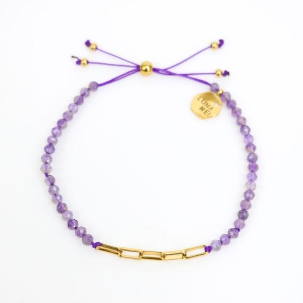 Purple beaded bracelet with gold accents on a white background
