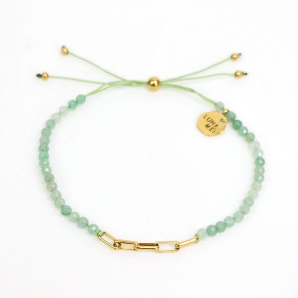 Green beaded bracelet with gold accents on a white background