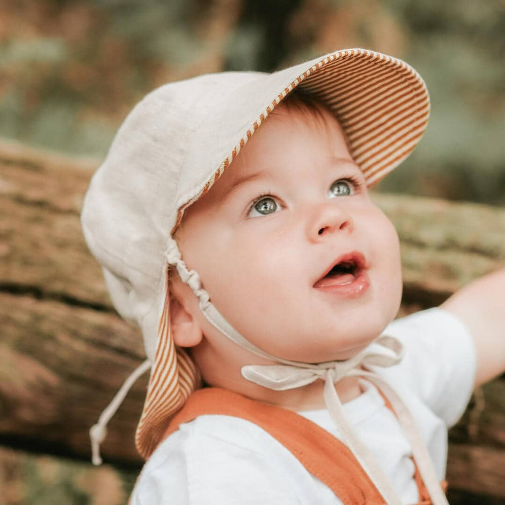 Child wearing a striped hat and white shirt outdoors