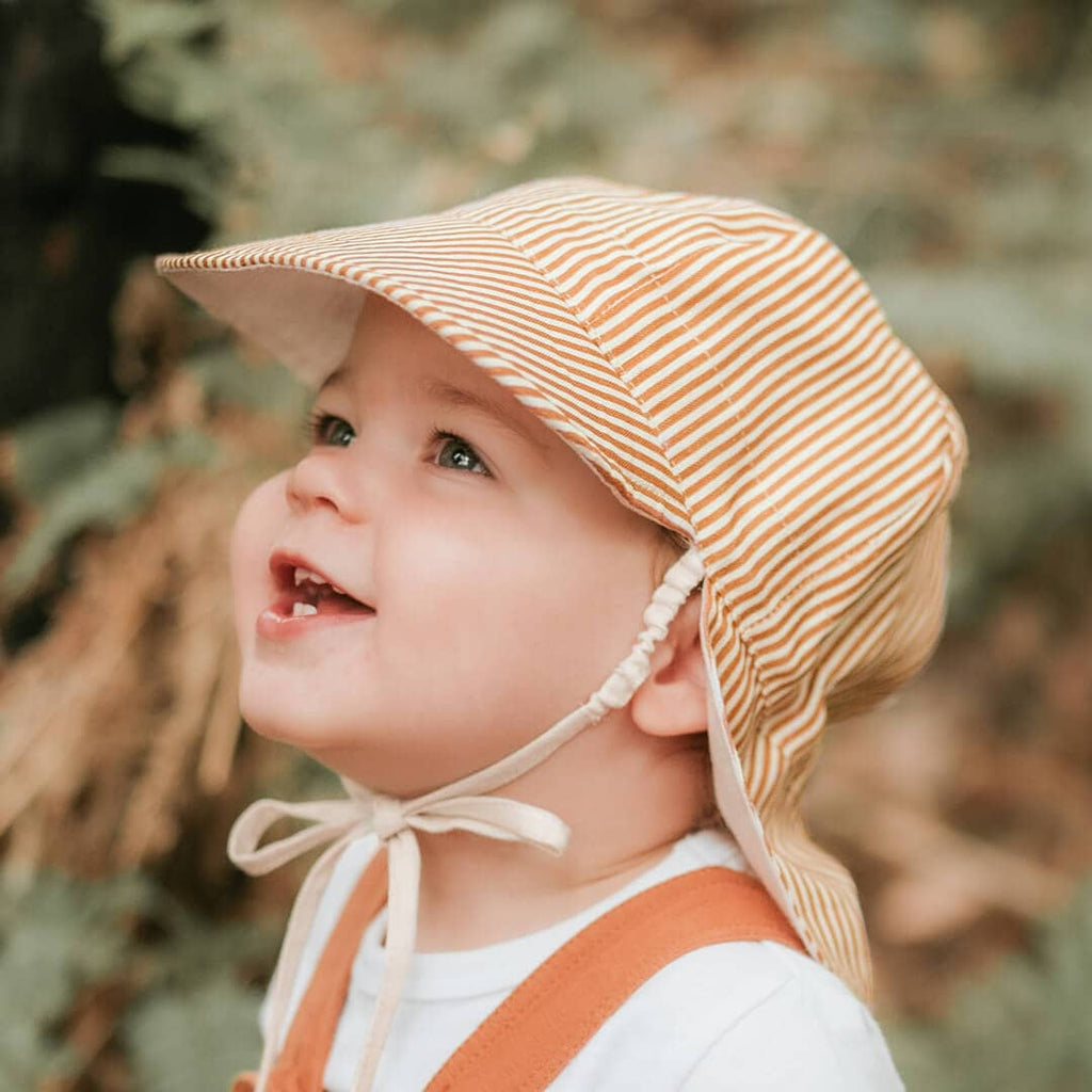 Child wearing a striped sun hat with a blurred natural background