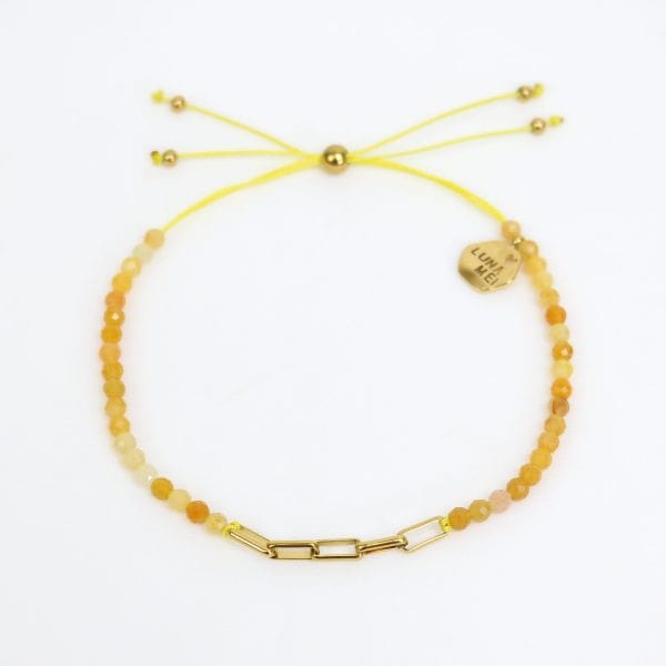 Yellow beaded bracelet with gold chain link on a white background