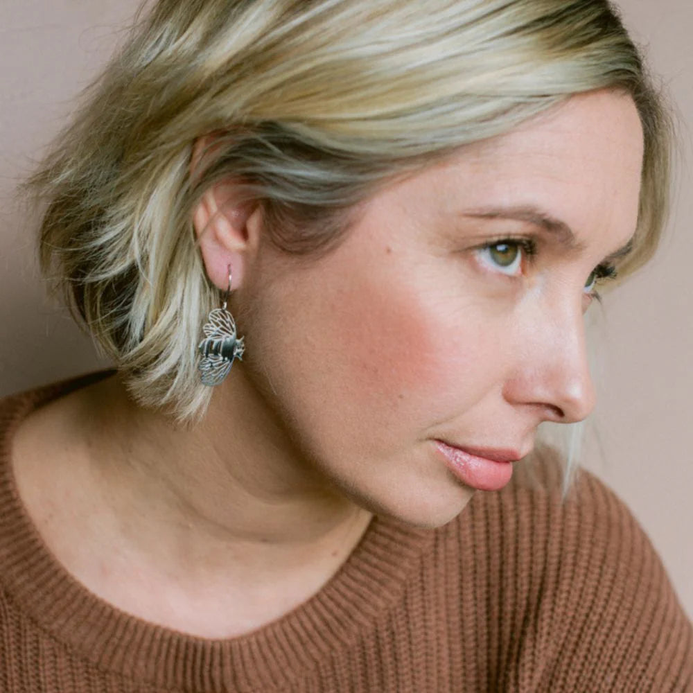 Woman wearing earrings with a neutral background