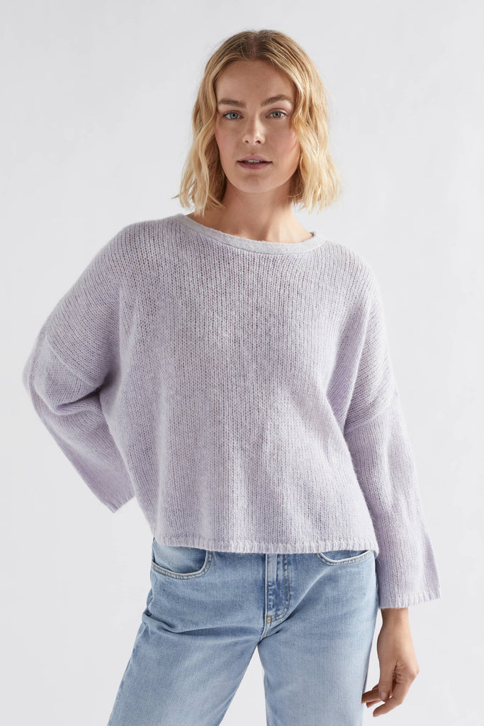 Woman wearing a light purple sweater and blue jeans on a white background