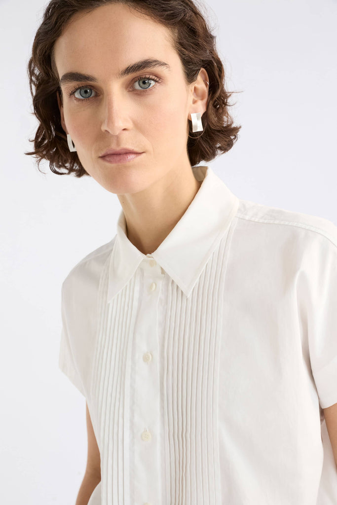 Woman wearing a white blouse against a plain background