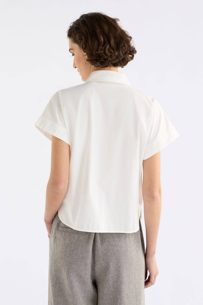 Person wearing a white blouse and gray pants on a white background