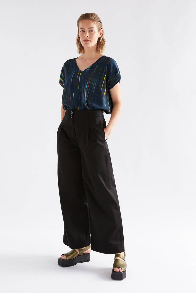 Woman wearing a dark blue top and black pants on a white background