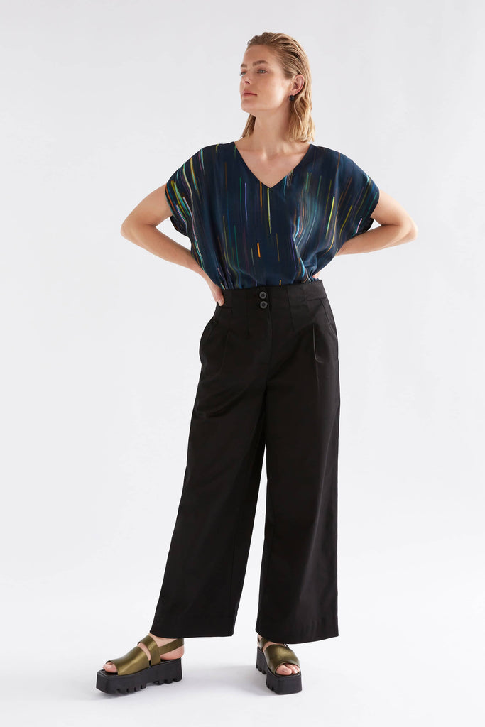 Woman wearing a dark blue striped top and black wide-leg pants on a white background