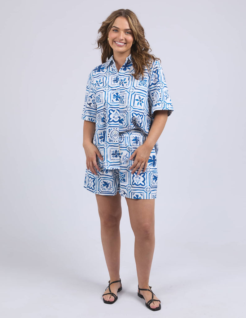 Woman wearing a blue and white patterned outfit on a plain background