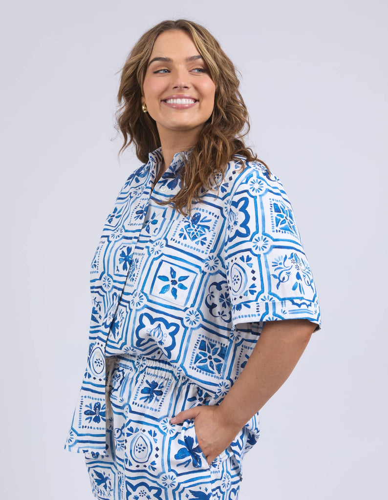 Woman wearing a blue and white patterned outfit on a plain background