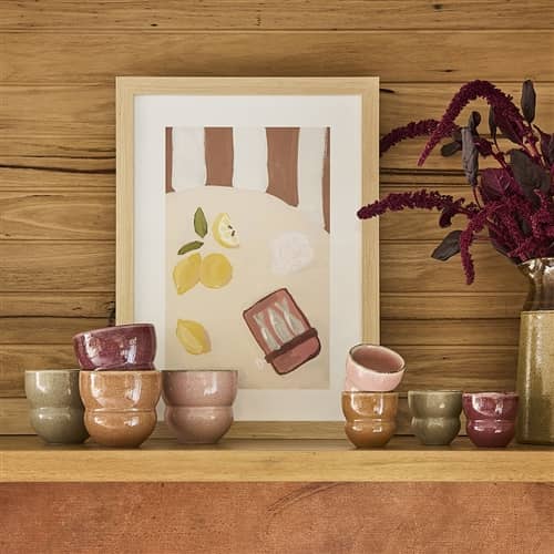 Decorative shelf with ceramic cups and a framed artwork on a wooden wall.