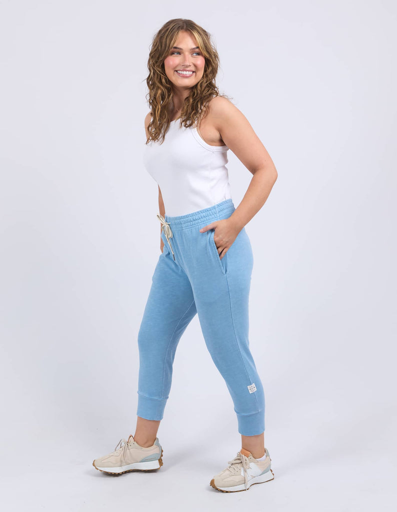 Woman wearing a white top and light blue jogger pants on a white background