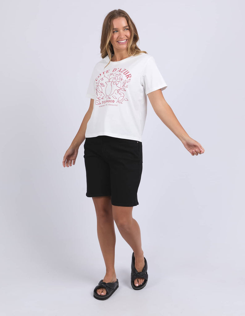 Woman wearing a white t-shirt with red text and black shorts on a white background