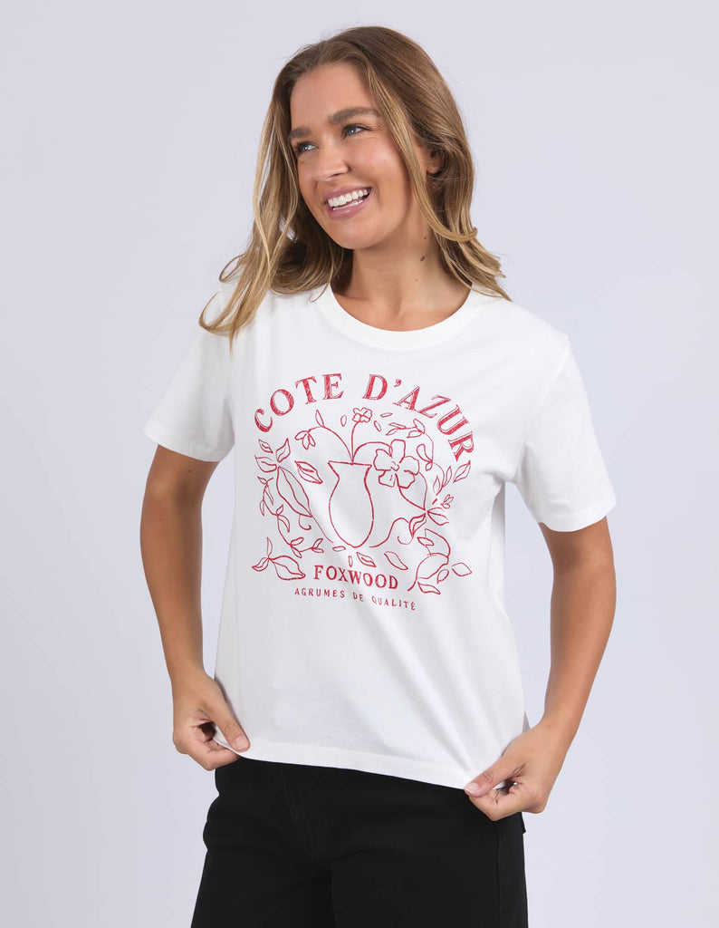 Woman wearing a white t-shirt with red graphics and text on a light gray background