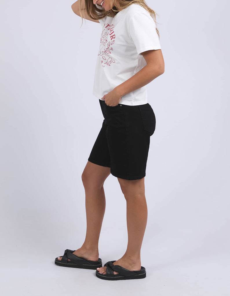 Person wearing a white t-shirt with red text and black shorts on a light gray background