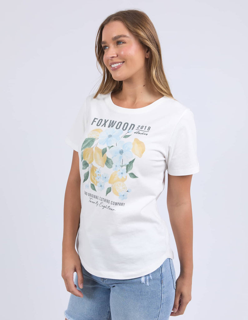 Woman wearing a white t-shirt with floral design and text on a plain background