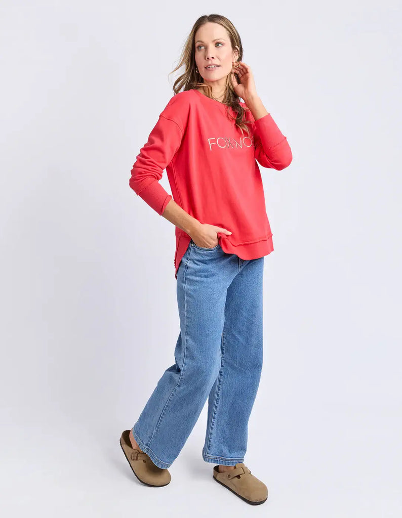 Woman wearing a red sweatshirt and blue jeans on a white background