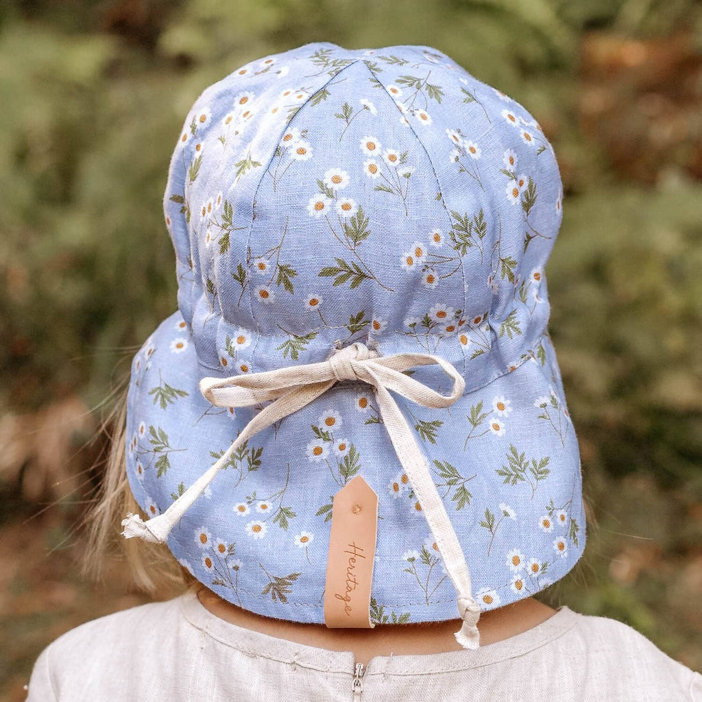 Child wearing a floral blue sun hat with a bow, standing outdoors.