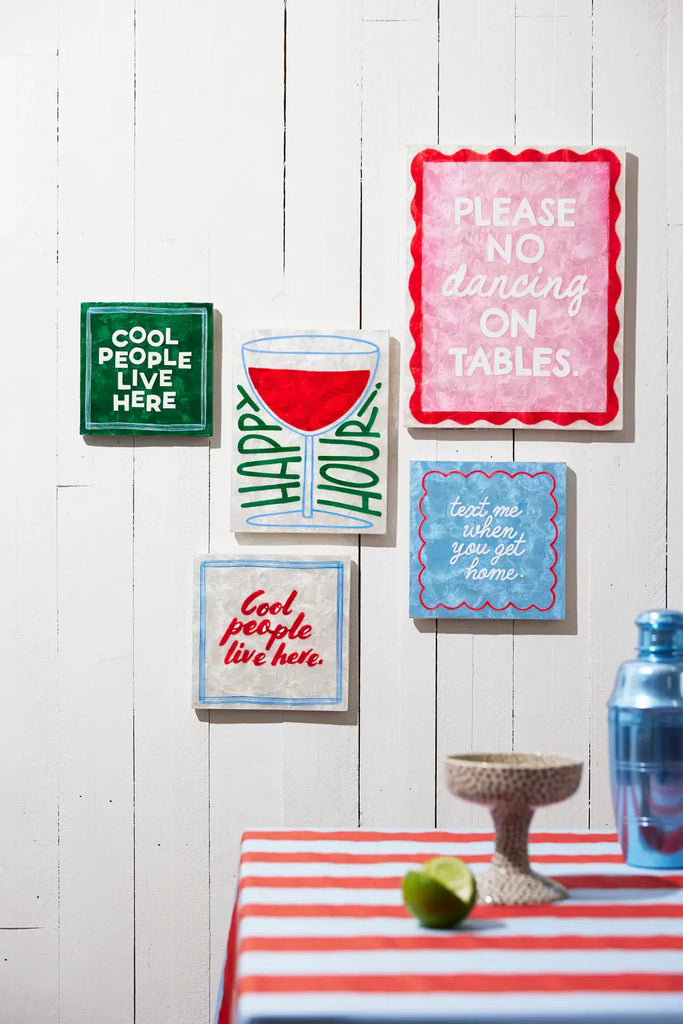 Decorative signs on a wall with a table and decorative items below.