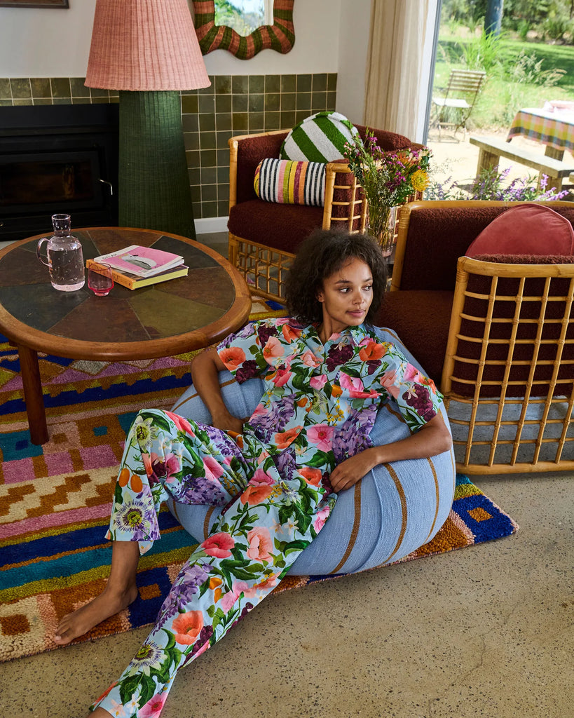 Woman in a floral outfit sitting on a colorful rug in a living room.