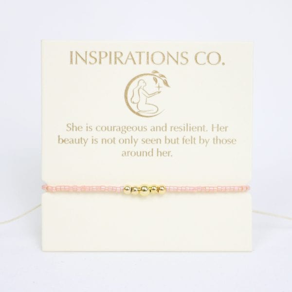 Pink bracelet with gold charm on a card from Inspirations Co.