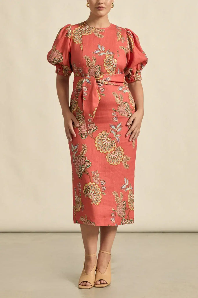 Woman wearing a red dress with gold floral patterns on a beige background