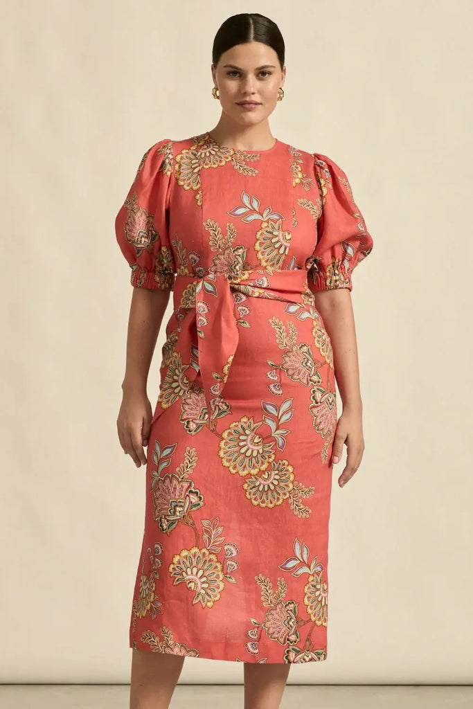 Woman wearing a red floral dress with puff sleeves against a beige background