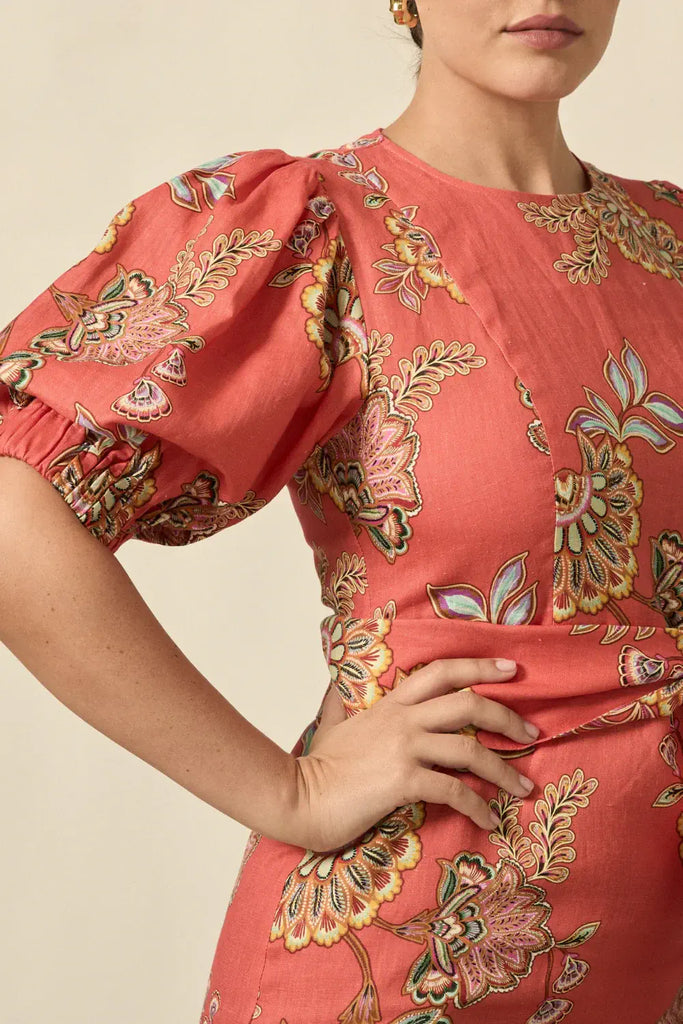 Person wearing a coral dress with floral pattern on a beige background