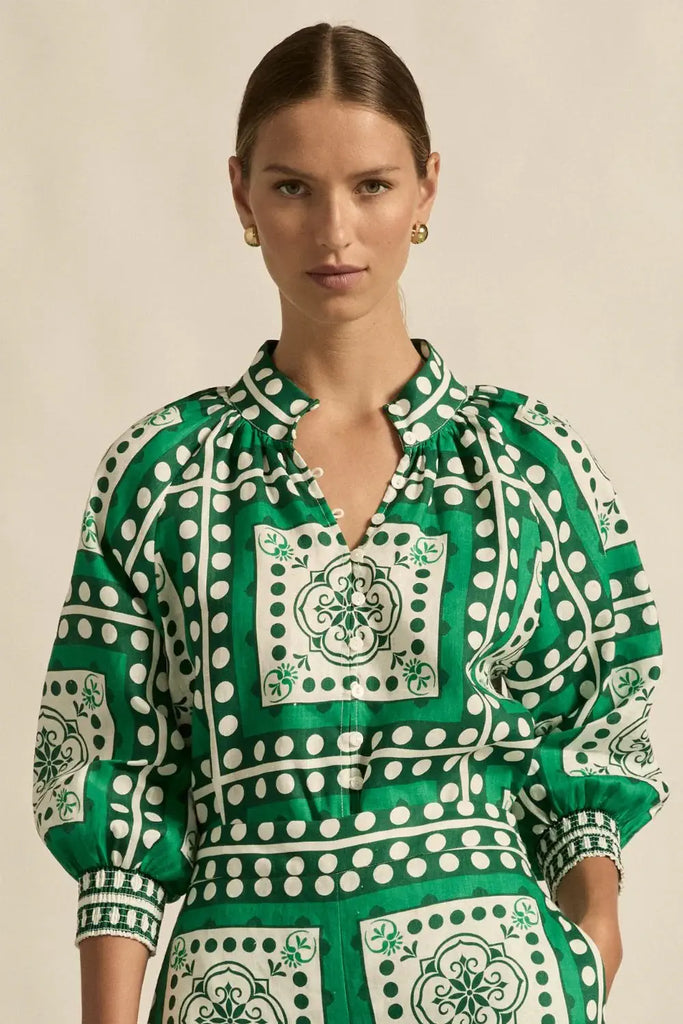 Woman wearing a green and white patterned blouse against a beige background