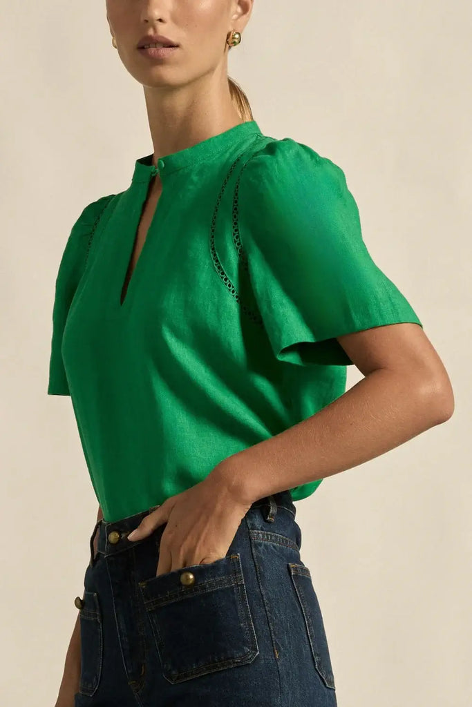Green blouse worn by a person on a beige background