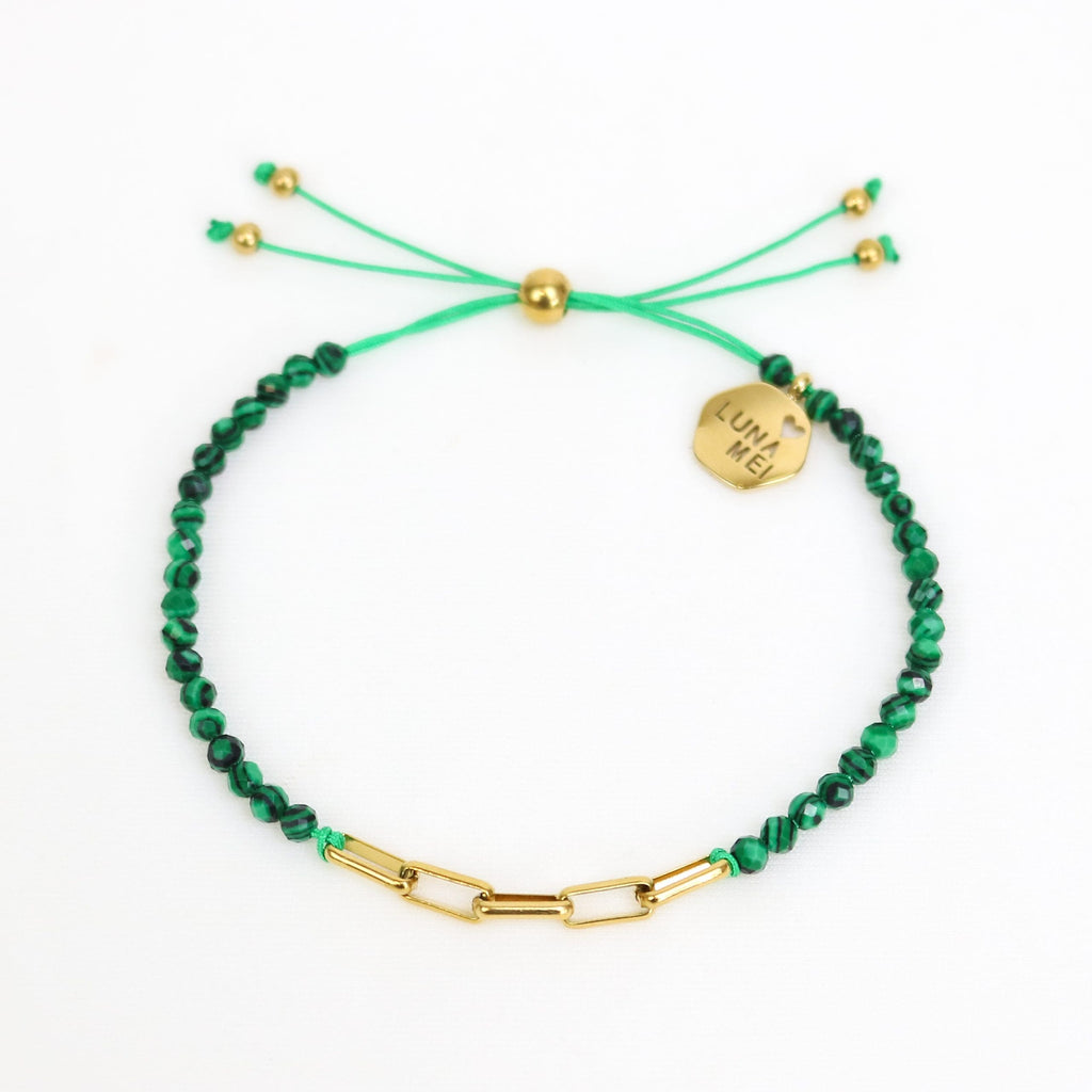 Green beaded bracelet with gold accents on a white background