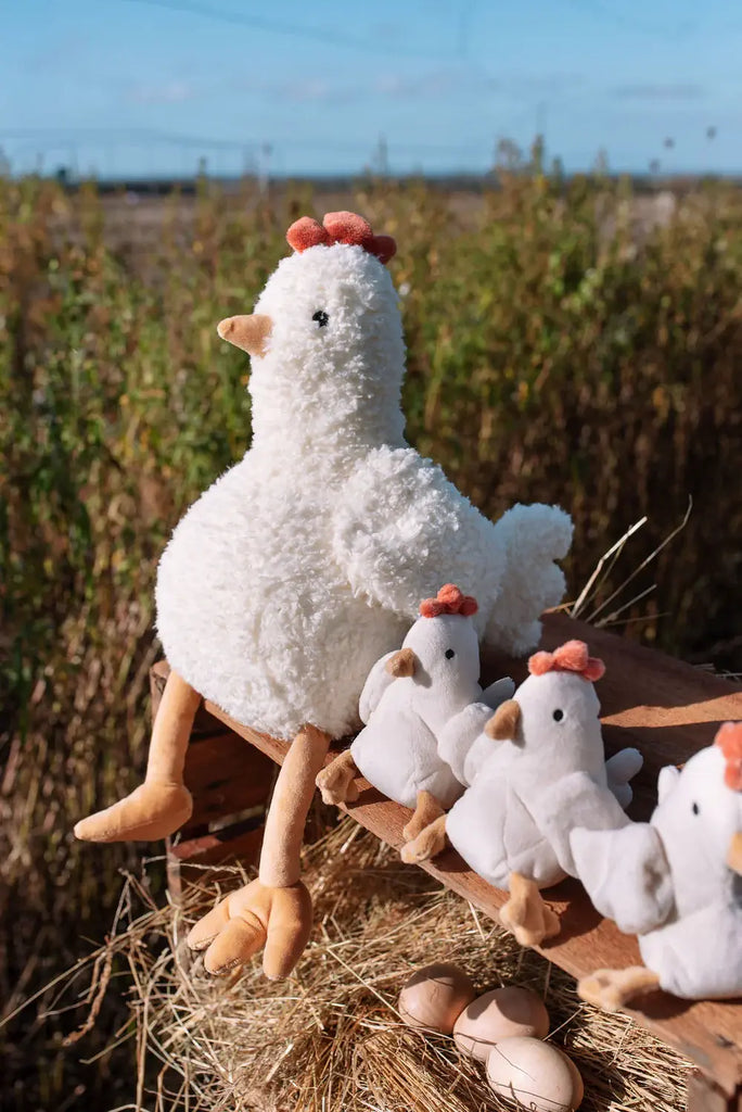 Plush chicken and chicks on a hay bale with a natural outdoor background