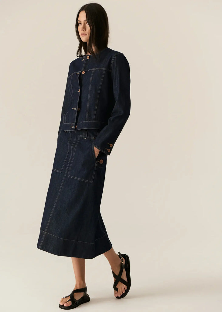 Woman wearing a dark denim jacket and skirt on a beige background