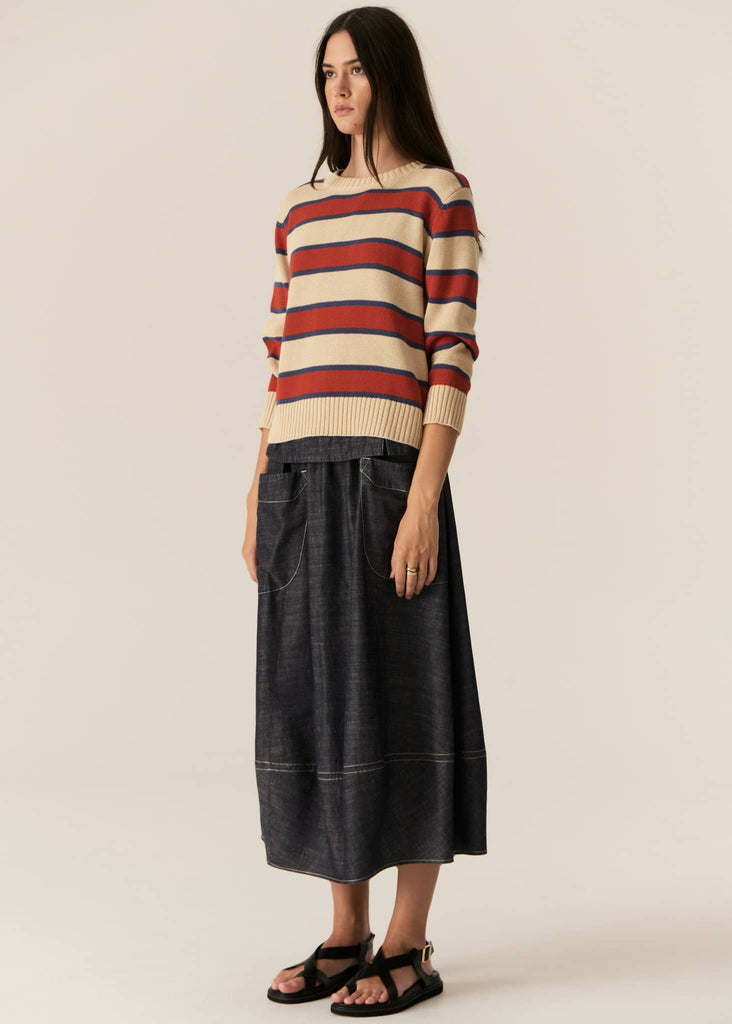 Woman wearing a striped sweater and black skirt on a plain background