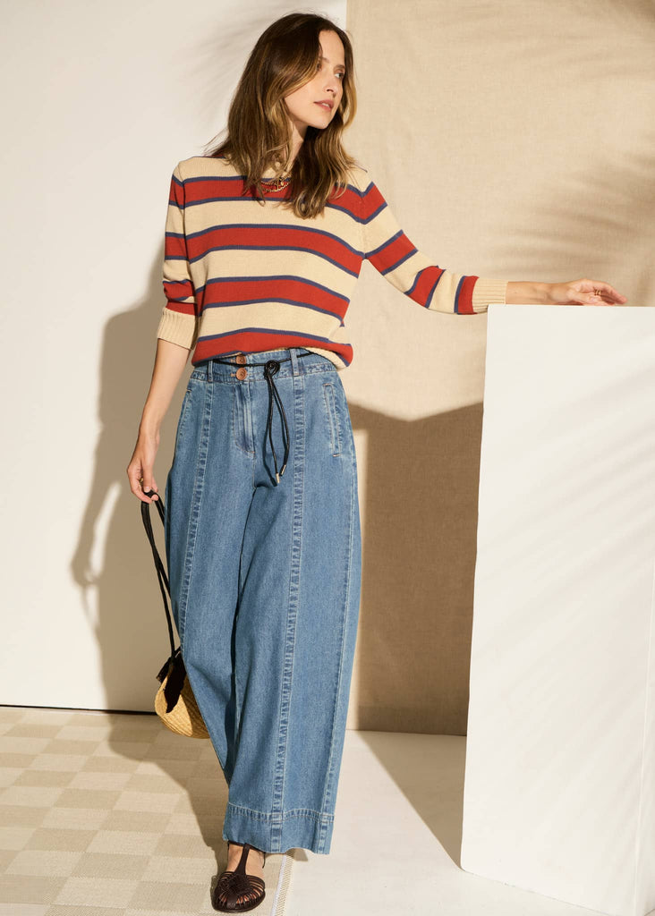 Woman wearing a striped sweater and jeans against a neutral background