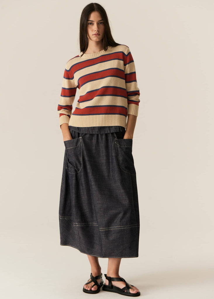 Woman wearing a striped sweater and black skirt on a plain background