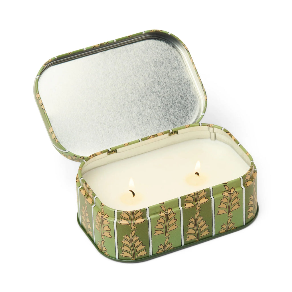 Scented candle in a decorative tin with a leaf pattern on a white background