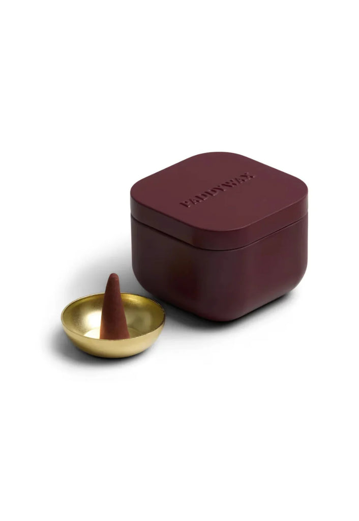 Maroon incense holder with a gold bowl and brown incense cone on a white background