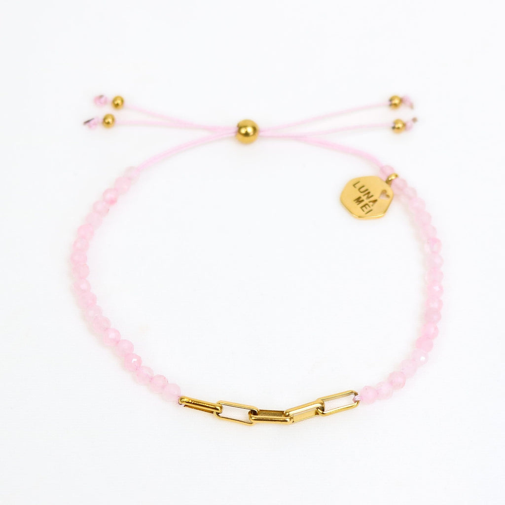 Pink bracelet with gold beads and clasp on a white background