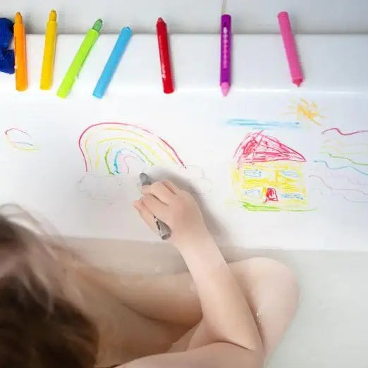 Child drawing with colorful crayons on a white sheet of paper