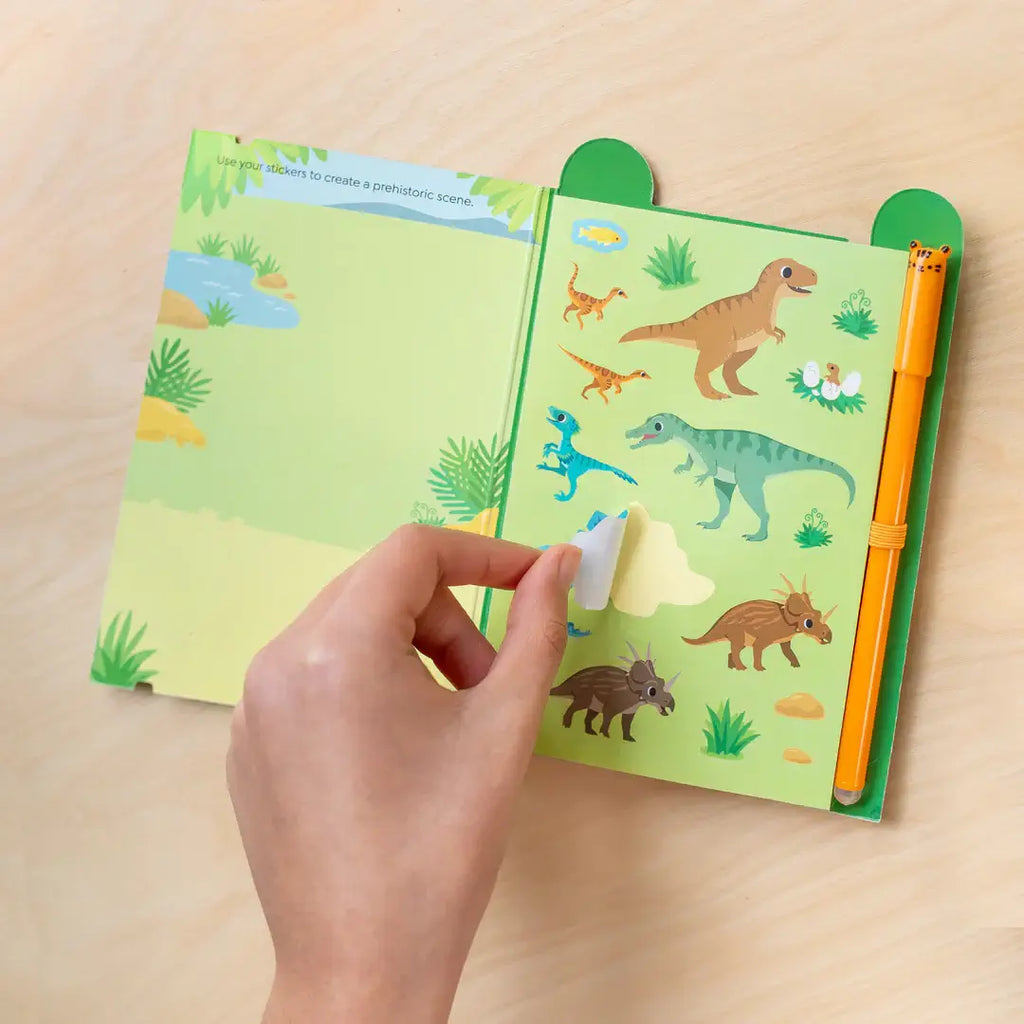 Children's activity book with dinosaur illustrations on a wooden surface