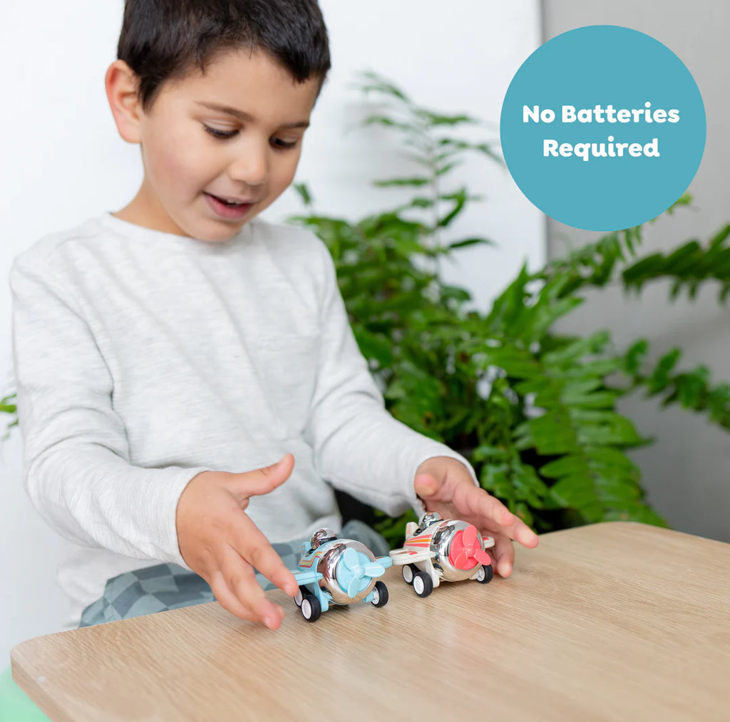 Child playing with a toy train set on a table with plants in the background
