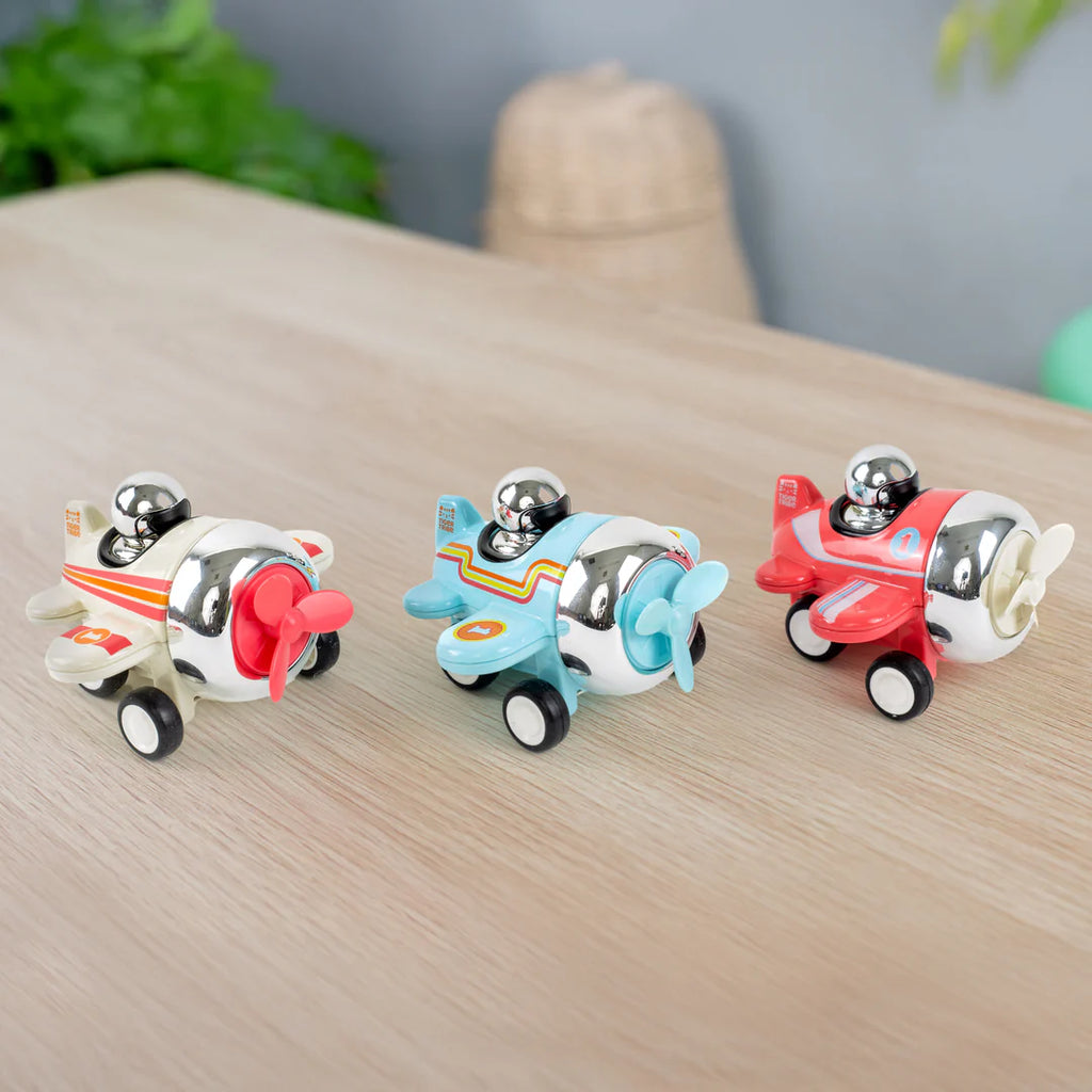 Three toy airplanes on a wooden surface with a blurred background