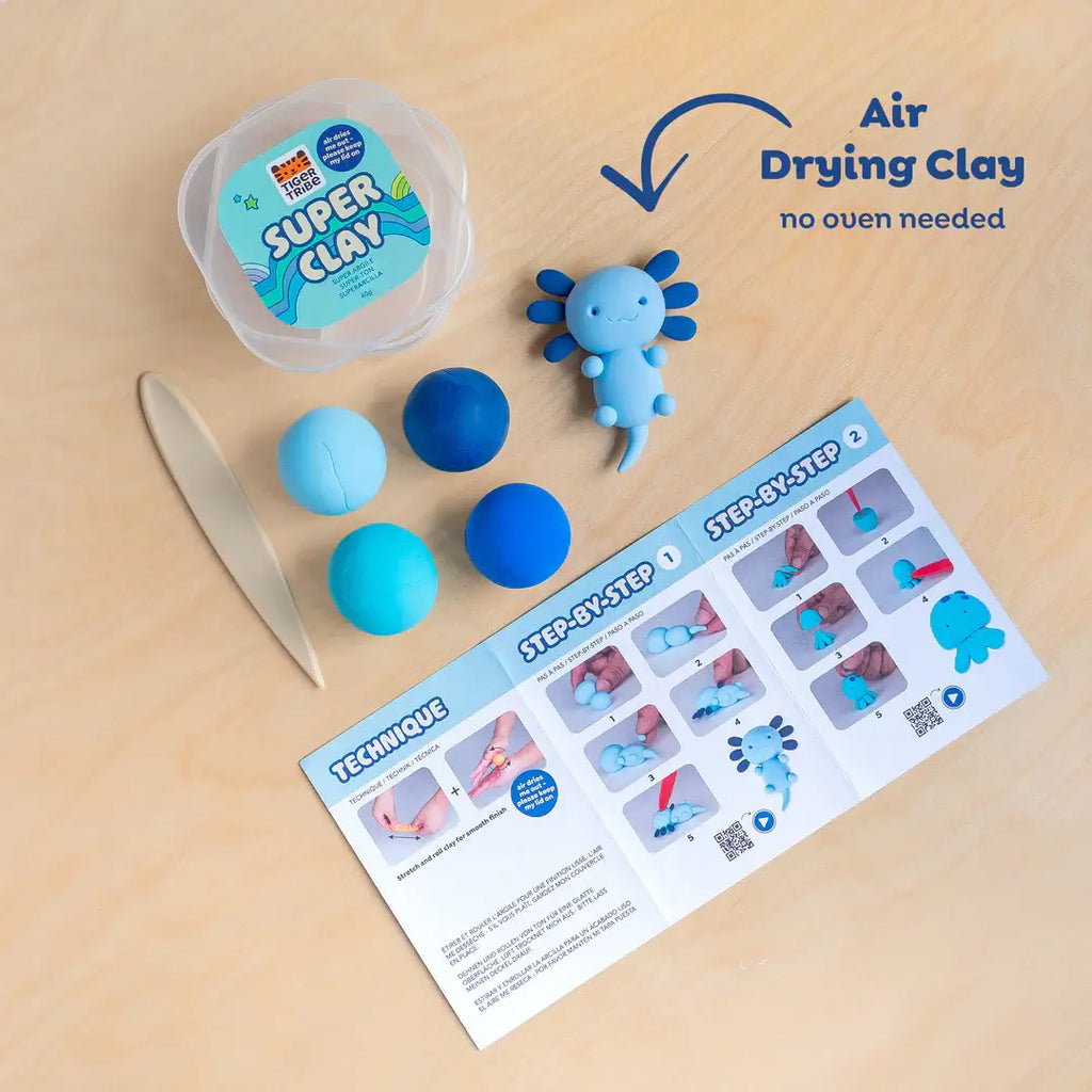 Super Clay kit with blue clay balls, a tool, and a step-by-step guide on a beige surface.