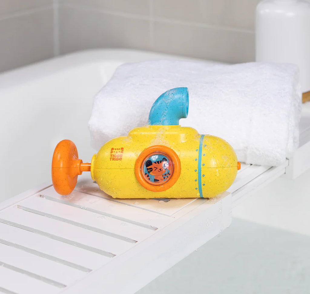 Yellow toy submarine with blue top and orange accents on a bathtub ledge.