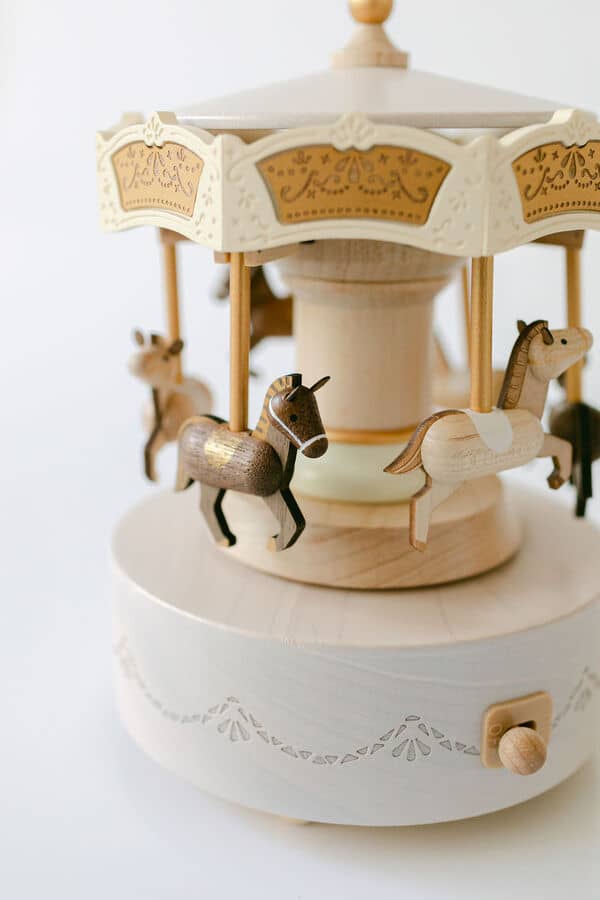 Wooden carousel toy with horses on a white background