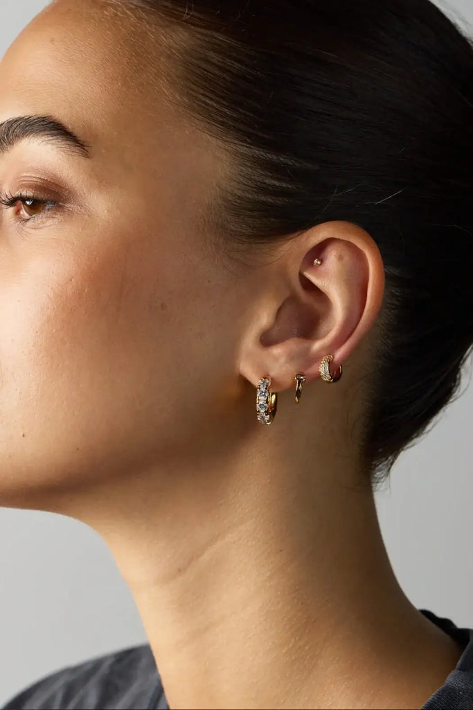 Close-up of a woman wearing hoop earrings with a neutral background