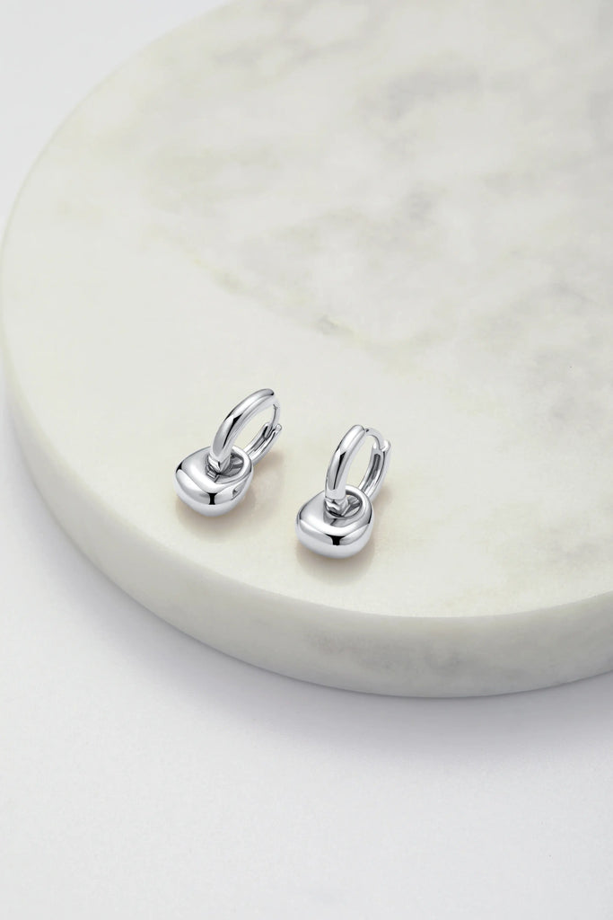Pair of silver earrings on a marble surface
