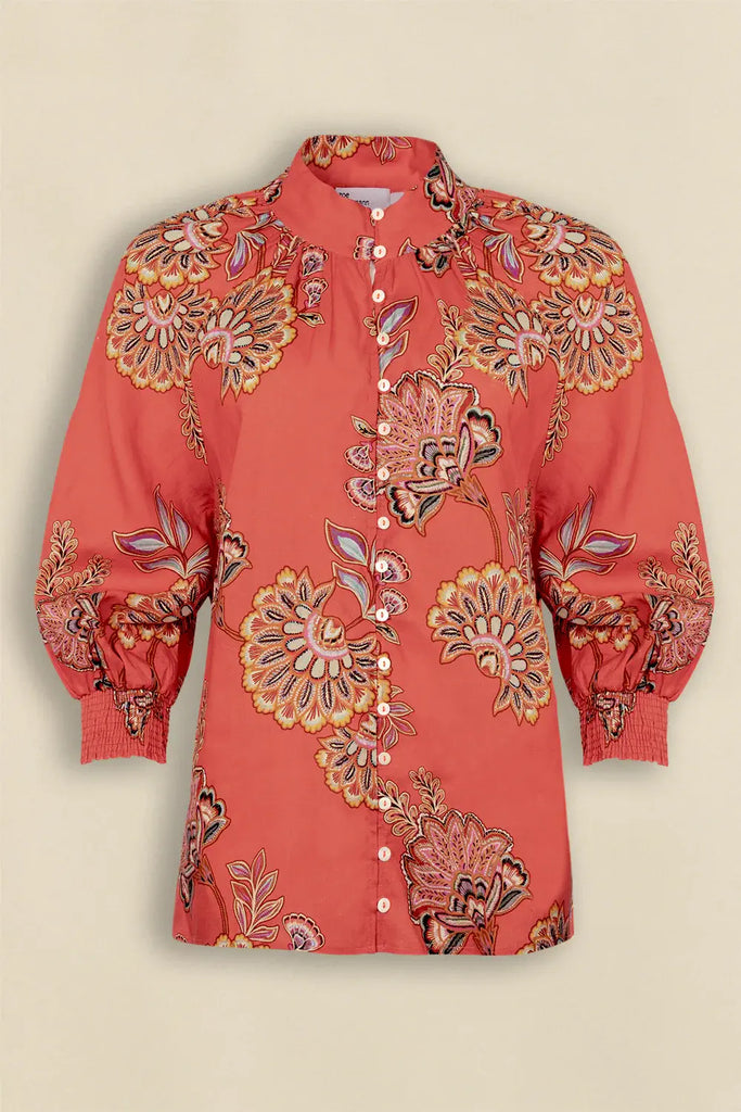 Red floral embroidered blouse on a beige background