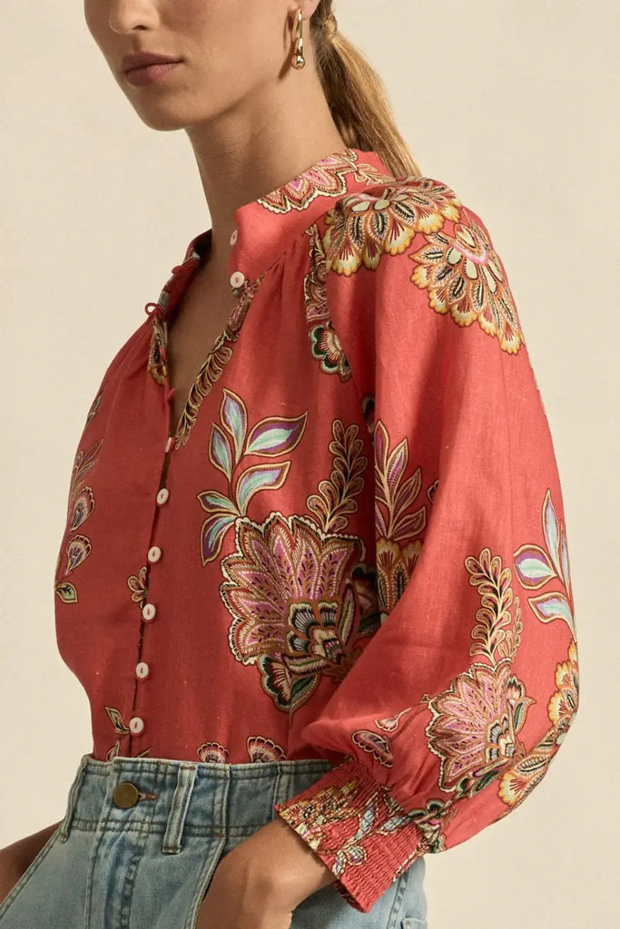 Red floral embroidered blouse worn by a person on a beige background